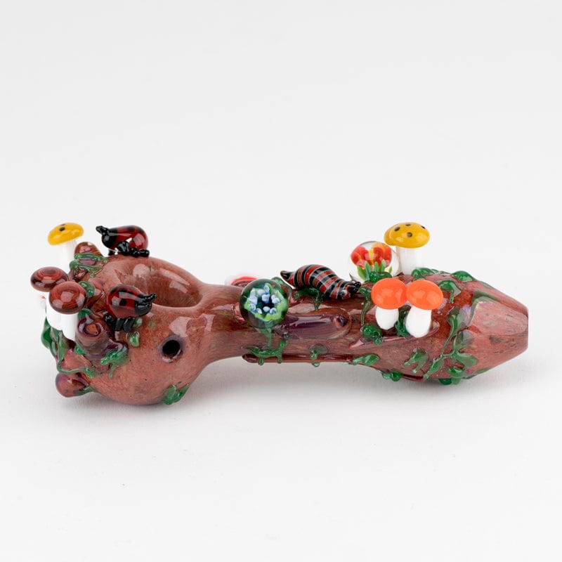 A close-up side view of the Ladybug Small Spoon Pipe, featuring sculpted ladybugs and mushrooms on a textured, brown glass body.