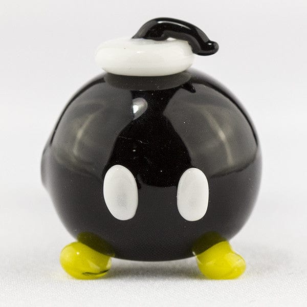 Front view of the Bomber Spoon Pipe, a small, black glass pipe with yellow feet, centered on a white surface.