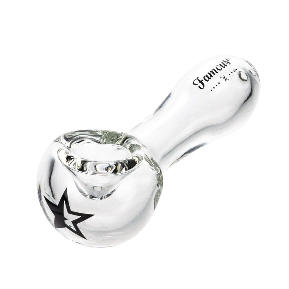 A side view of the Famous X 4" Spoon Pipe, showcasing its clear glass construction and curved design.