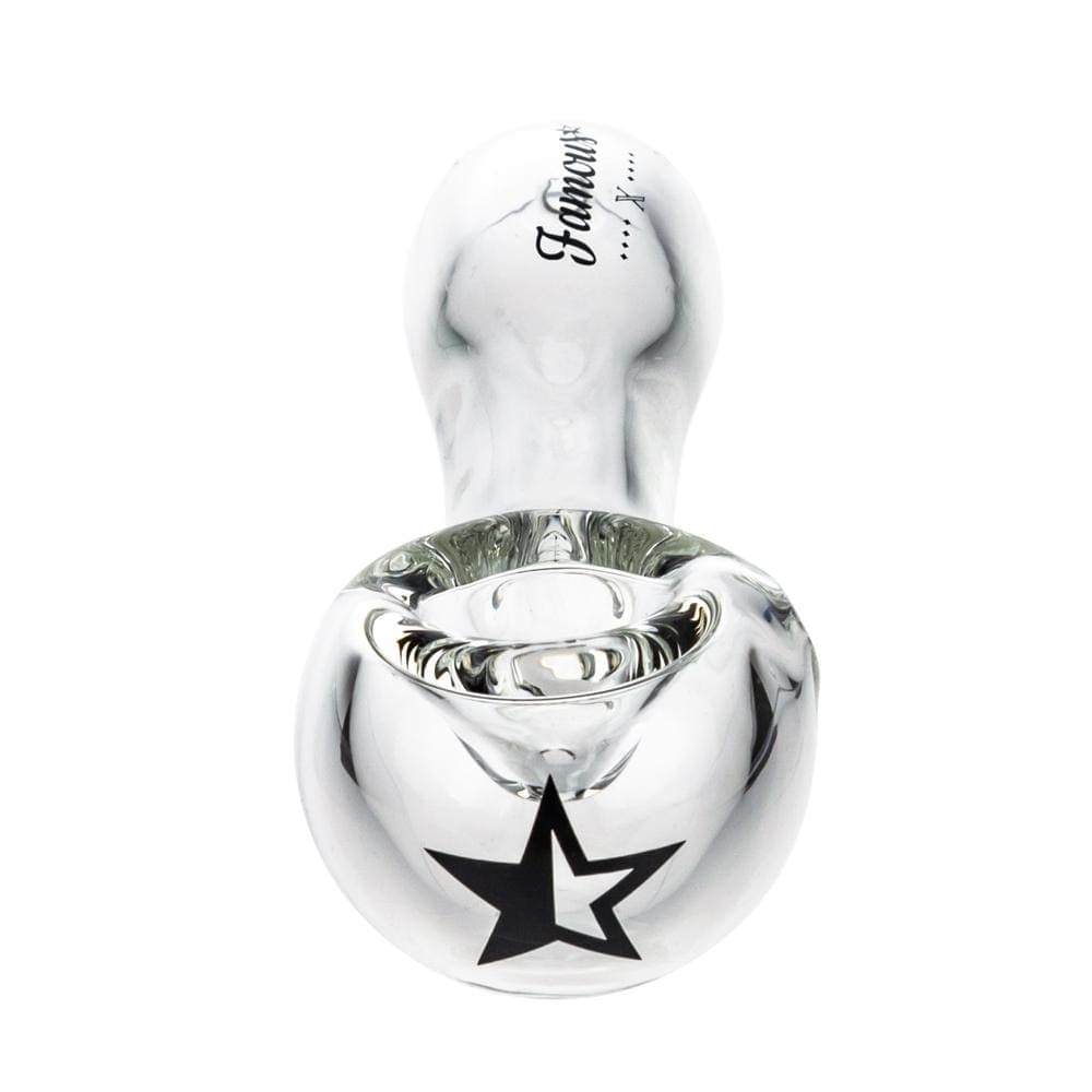 A close-up, angled view of the Famous X 4" Spoon Pipe in clear glass, showing its curved bowl and smooth finish.