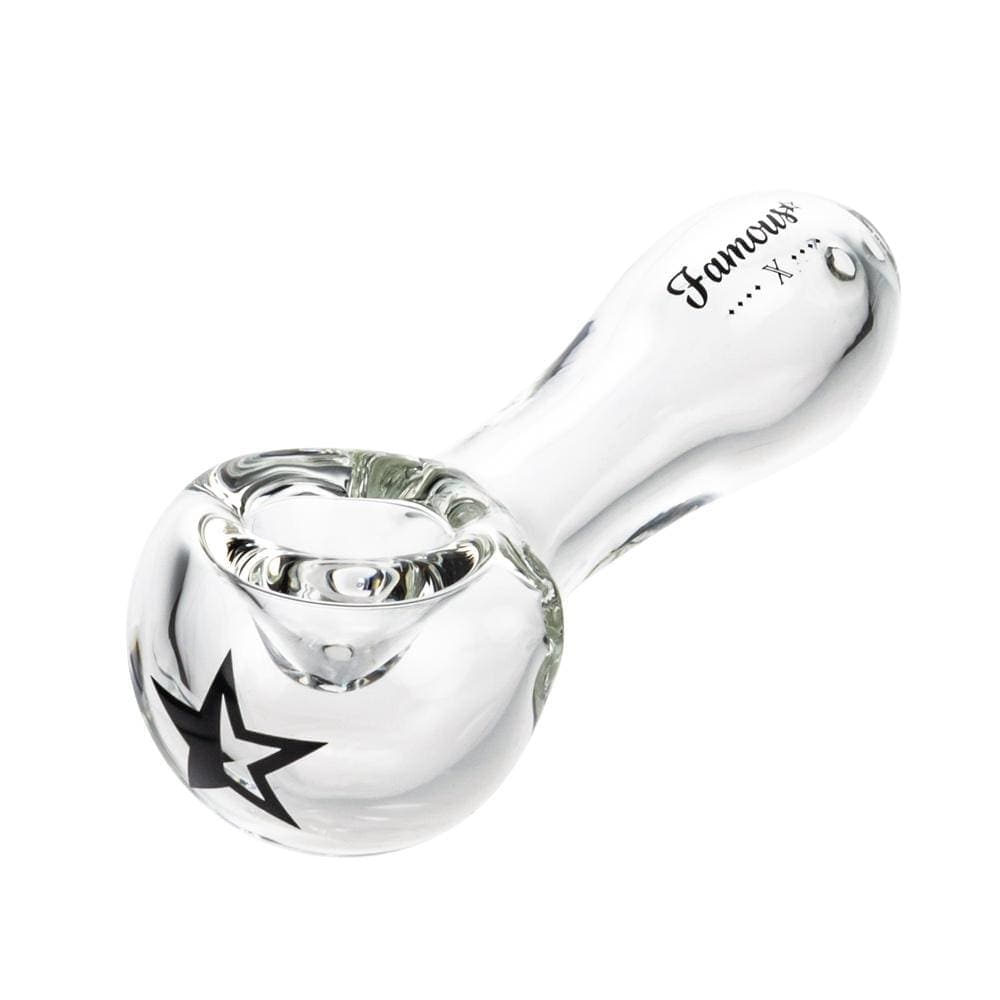 A side view of the Famous X 4" Spoon Pipe in clear glass, showcasing its curved design and smooth finish.