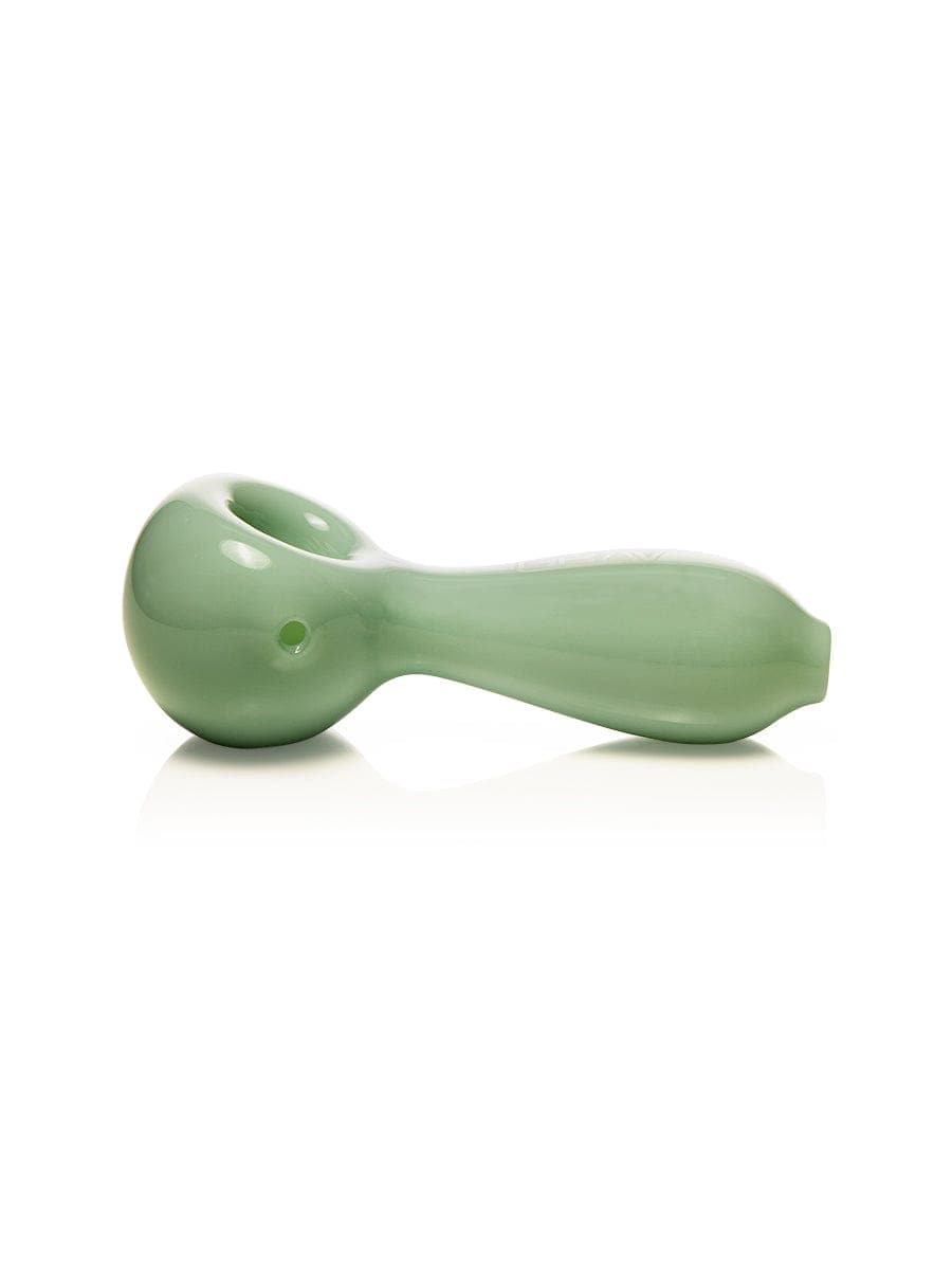 A side view of the GRAV® Large Spoon, a clear glass pipe with a curved design, reflecting on a glossy surface.