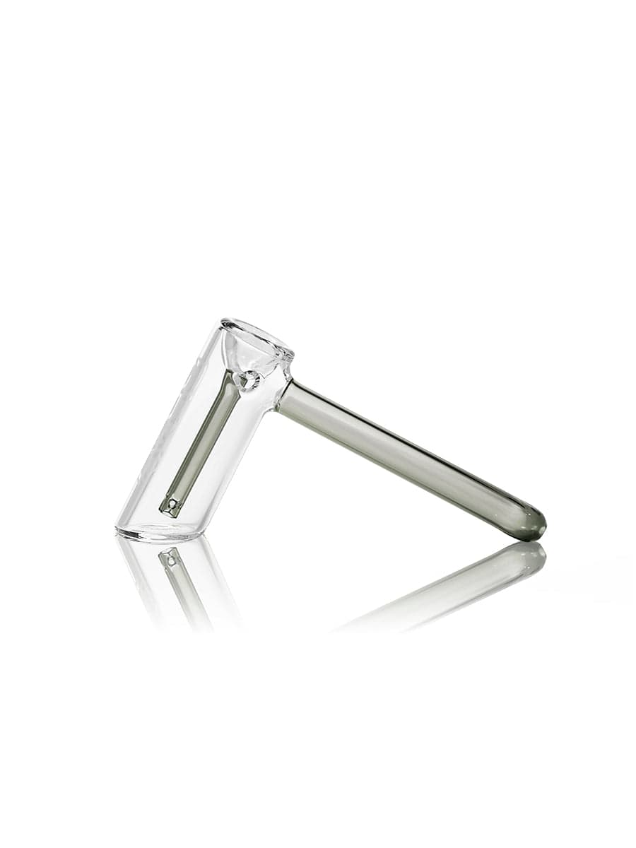A side view of the GRAV® Hammer Bubbler, showing its clear glass construction and sleek, cylindrical form reflected on a dark surface.
