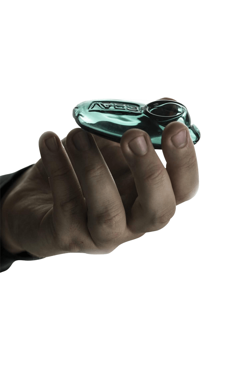 A hand holds the Grav Labs Pebble Spoon, showcasing its smooth, minimalist design against a stark white background.