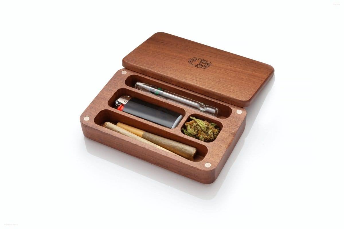 Top-down view of the Oakleaf Mini Case Stash Box with Glass One Hitter open, displaying its wooden compartments and a small glass pipe inside.
