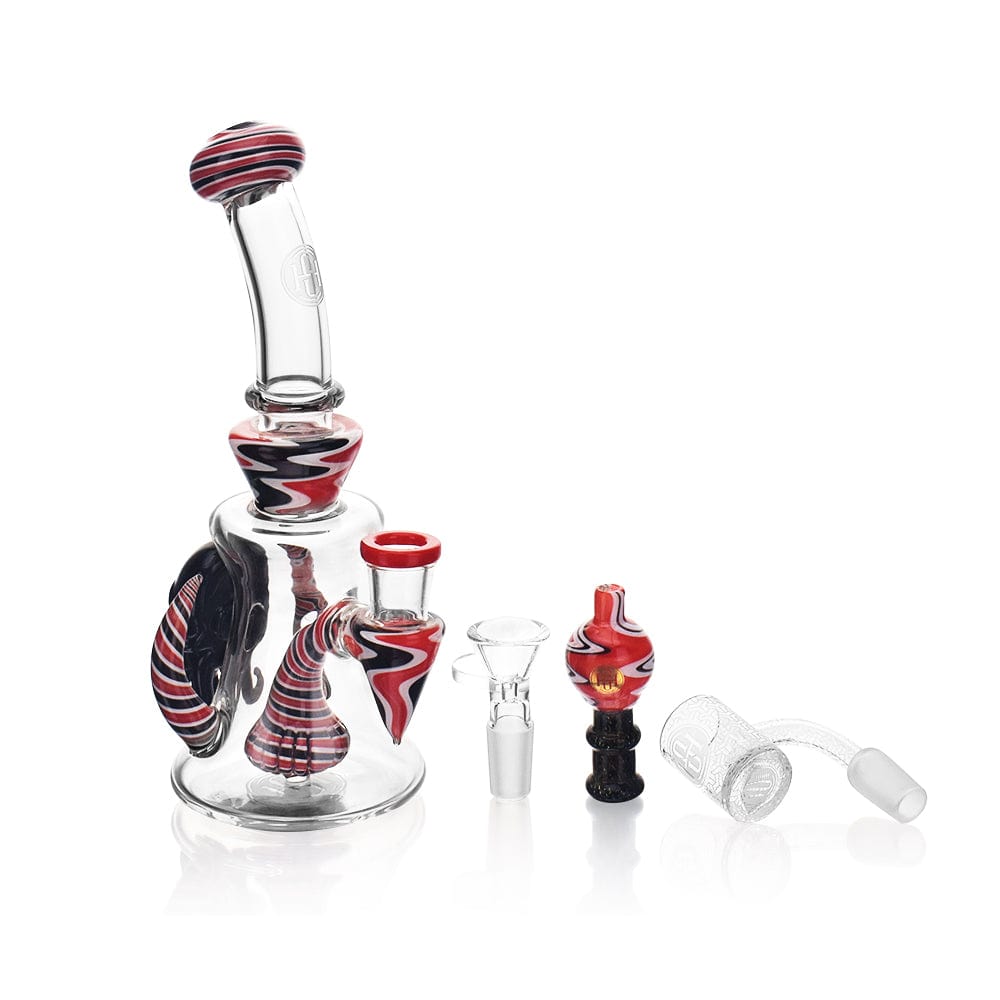 A three-quarter view of the High Society - Tulu Premium Wig Wag Concentrate Rig, displaying its red and black patterned glass with a detachable mouthpiece.