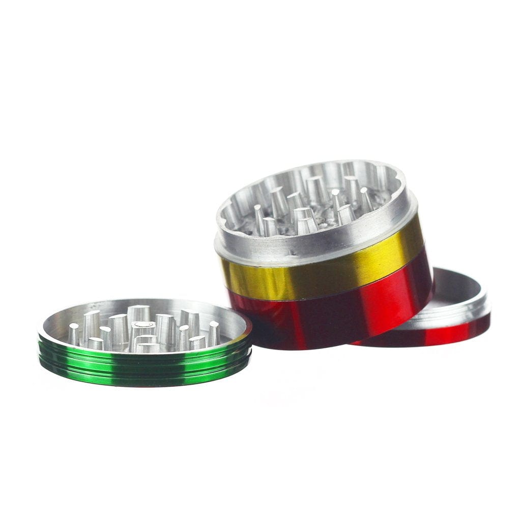 A disassembled Rasta Grinder rests on a white surface, revealing its metallic, multi-tiered construction in a high-angle view.