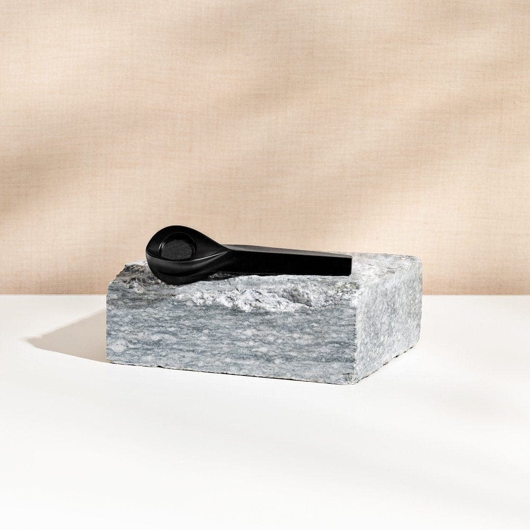 A minimalist shot features the KØL Mini 2.0 Titanium Travel Utensil Set resting on a textured gray block.