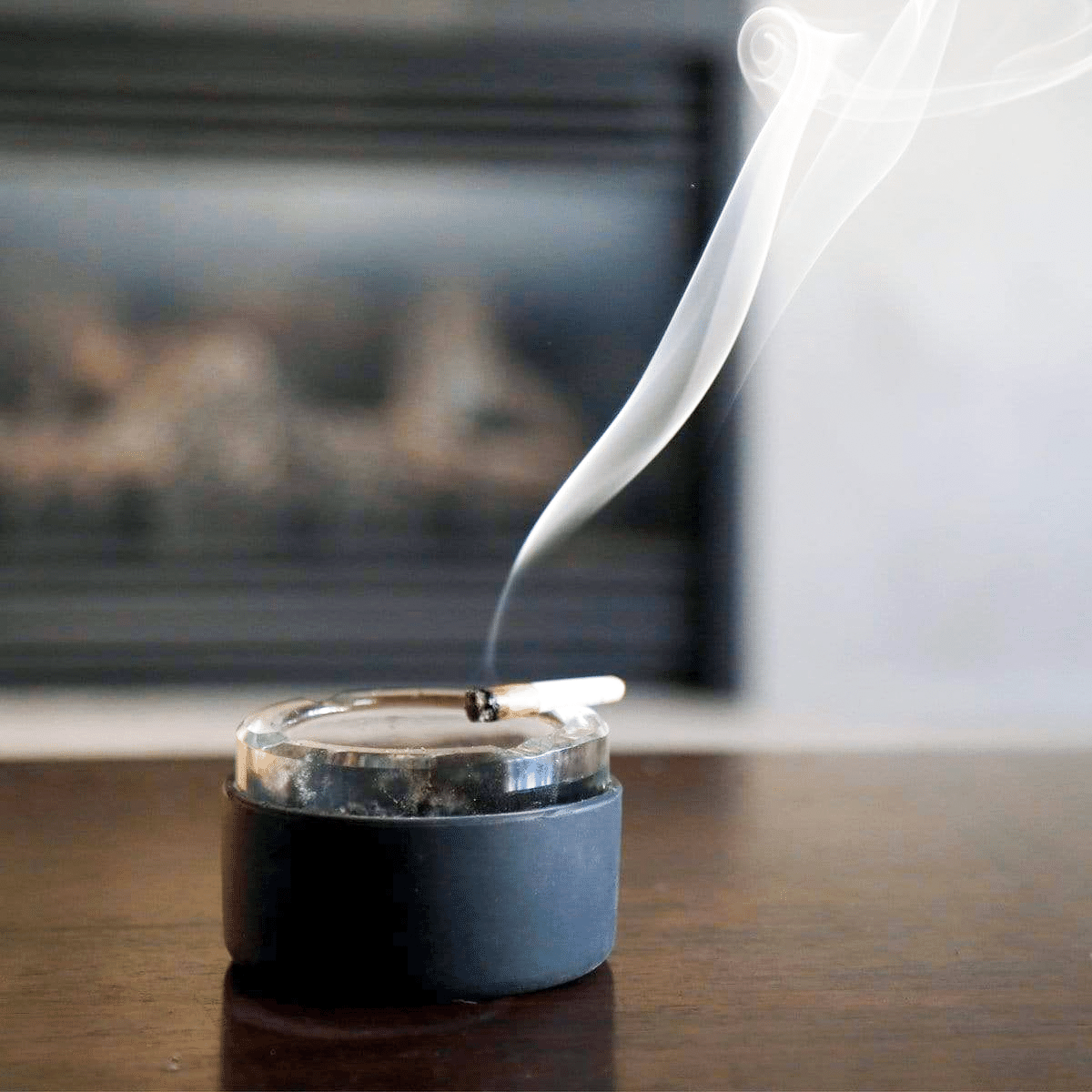 A close-up view of smoke rising from a recently used Ashtray on a reflective surface.