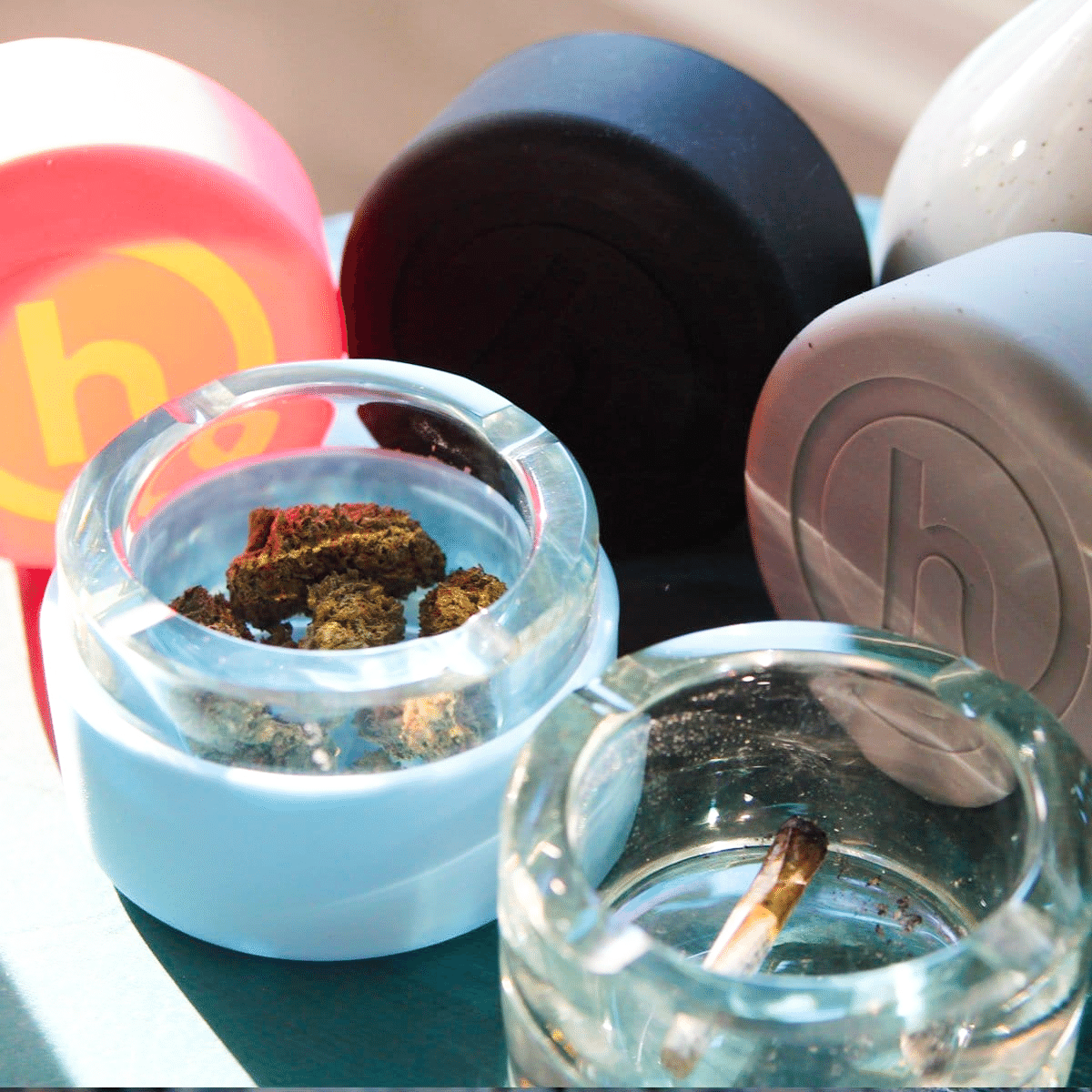 An overhead view of the Ashtray filled with ash, positioned among colorful spherical objects on a neutral surface.