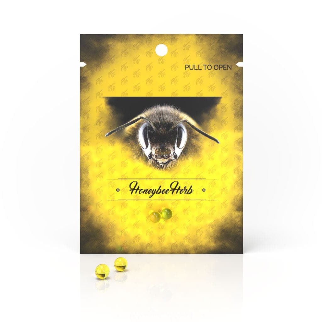 Front view of Honeybee Herb Honey Pearls, small golden spheres displayed on a dark, textured background.