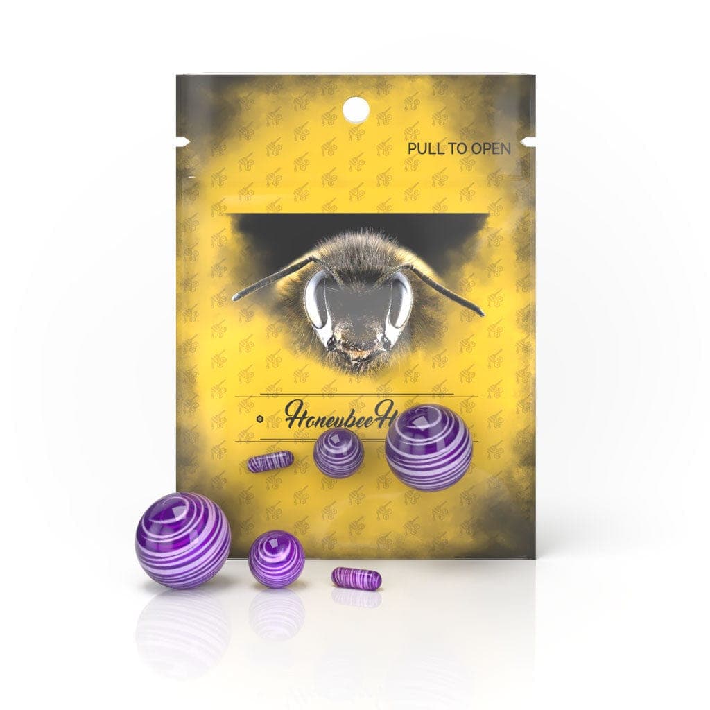 The Honeybee Herb Dab Marble Set is displayed in a close-up, showing the translucent purple marbles against a patterned gold background.