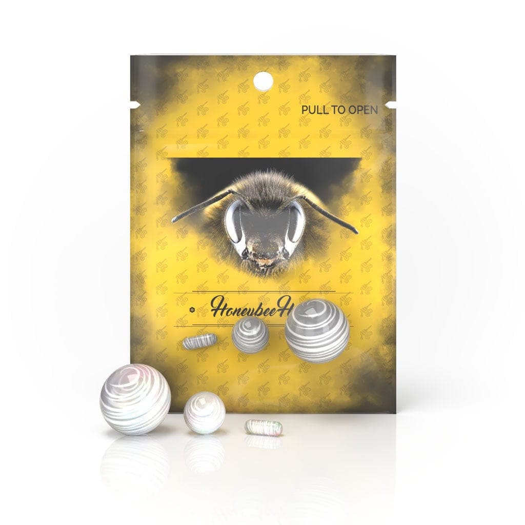 A close-up, angled view of the Honeybee Herb Dab Marble Set, showing three spherical marbles on a reflective surface.