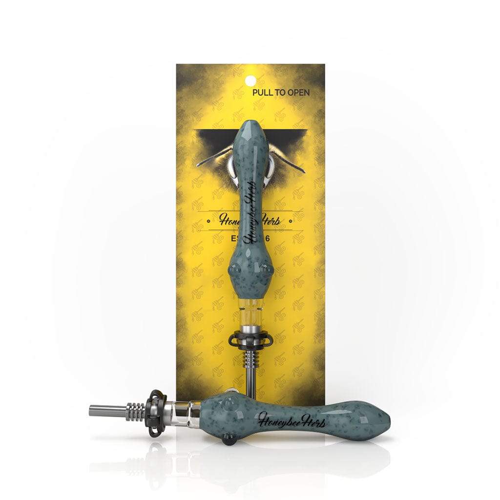 Front-angle view of a green Speckled Glass Nectar Collector resting horizontally with a matching upright piece against yellow branded packaging.