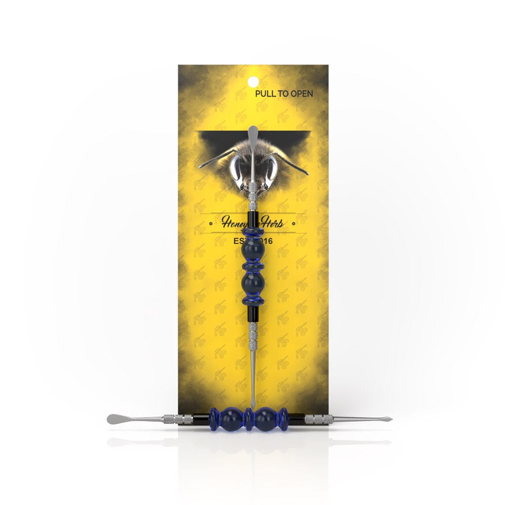 A close-up of the Bliss Dab Tool, showing its metallic point against a golden floral backdrop.