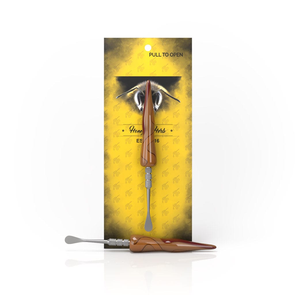 Front-facing image of the Swirl Tide Dab Tool against yellow branded carding, with one dark-green handled tool upright and a second lying horizontally in front.