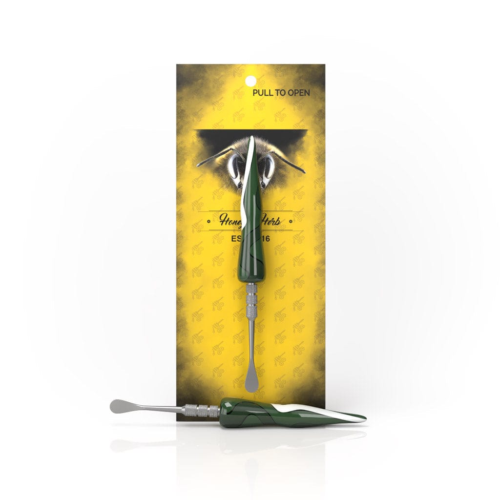 Front view of the Green Swirl Tide Dab Tool against yellow packaging with one tool mounted and a second lying reflective below.