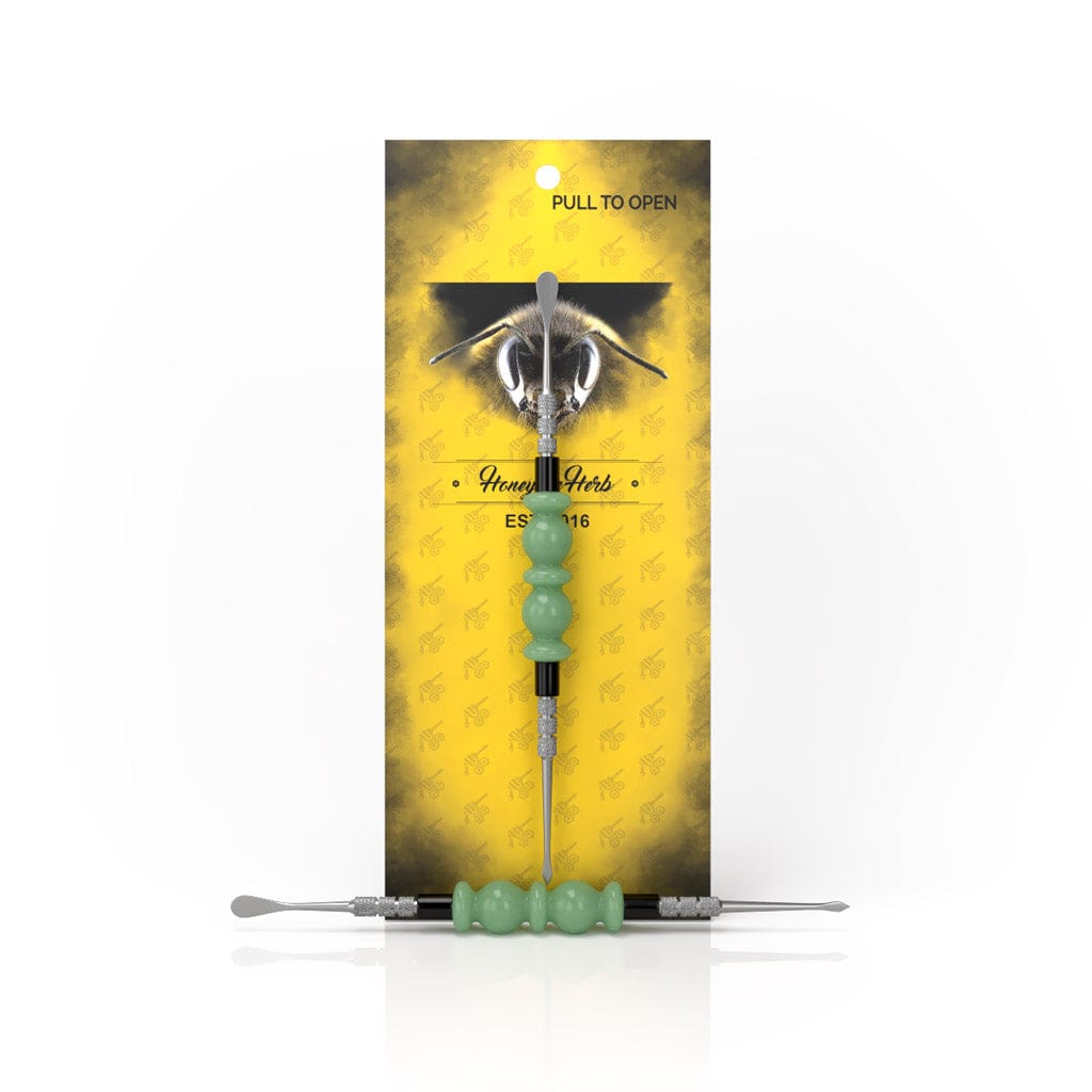 A close-up, angled view of the Bliss Dab Tool with a metallic tip against a bright yellow background.