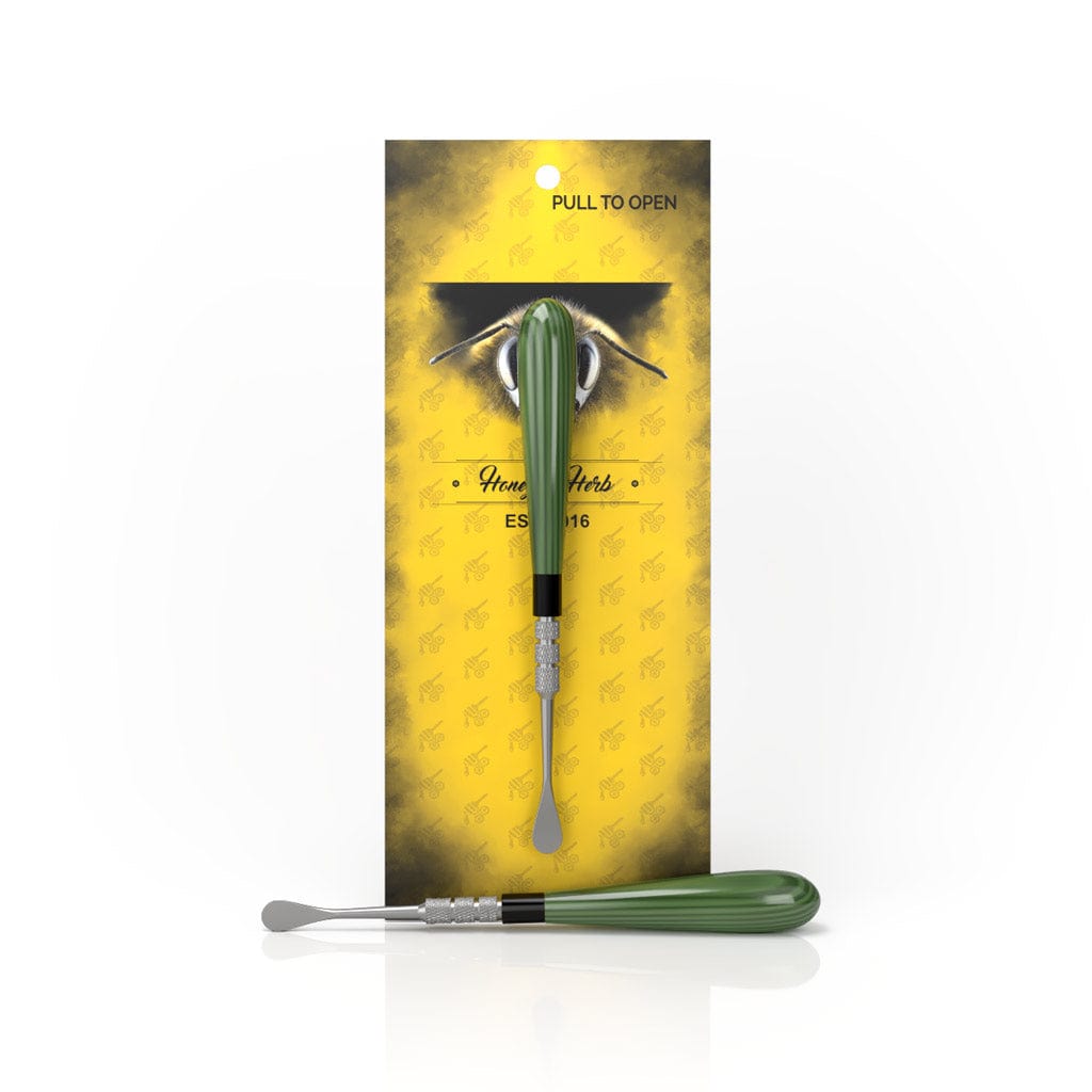 A close-up of the Classic Dab Tool with a metallic tip, packaged against a yellow background with “Pull to Open” text.