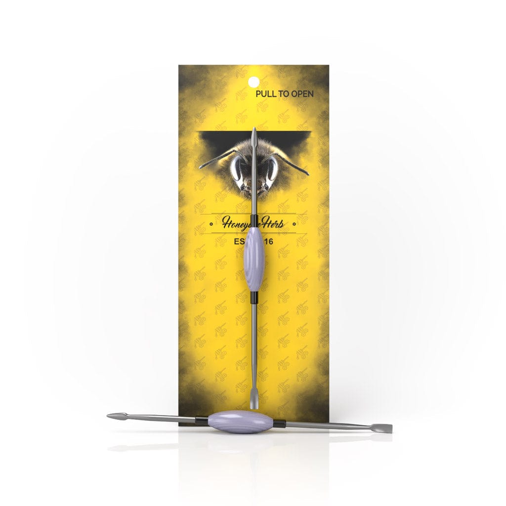 A close-up shot of the Oval Dab Tool, displaying its smooth, curved design against a blurred golden background.