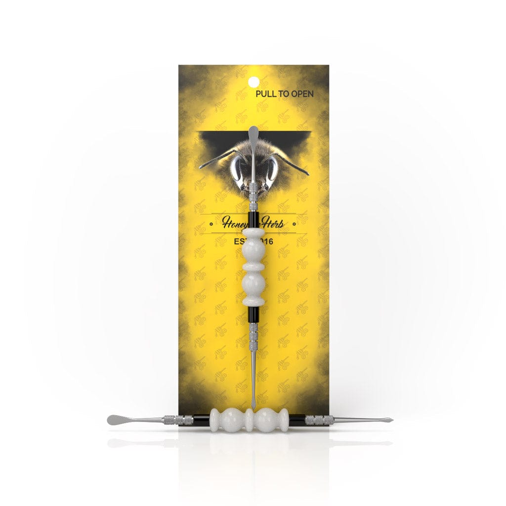 A close-up of the Bliss Dab Tool featuring a metallic tip against a textured golden background.