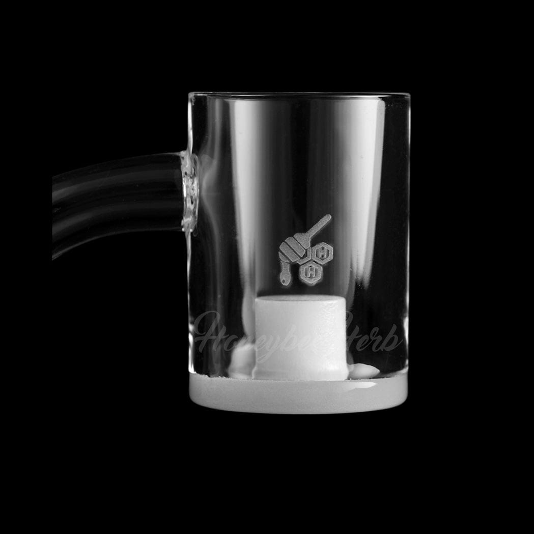 Close-up front view of the HONEY & MILK CORE REACTOR QUARTZ BANGER - 45Â° DEGREE | YL showing a clear cylindrical quartz cup with a frosted bottom and a small honey-dipper logo on a black background