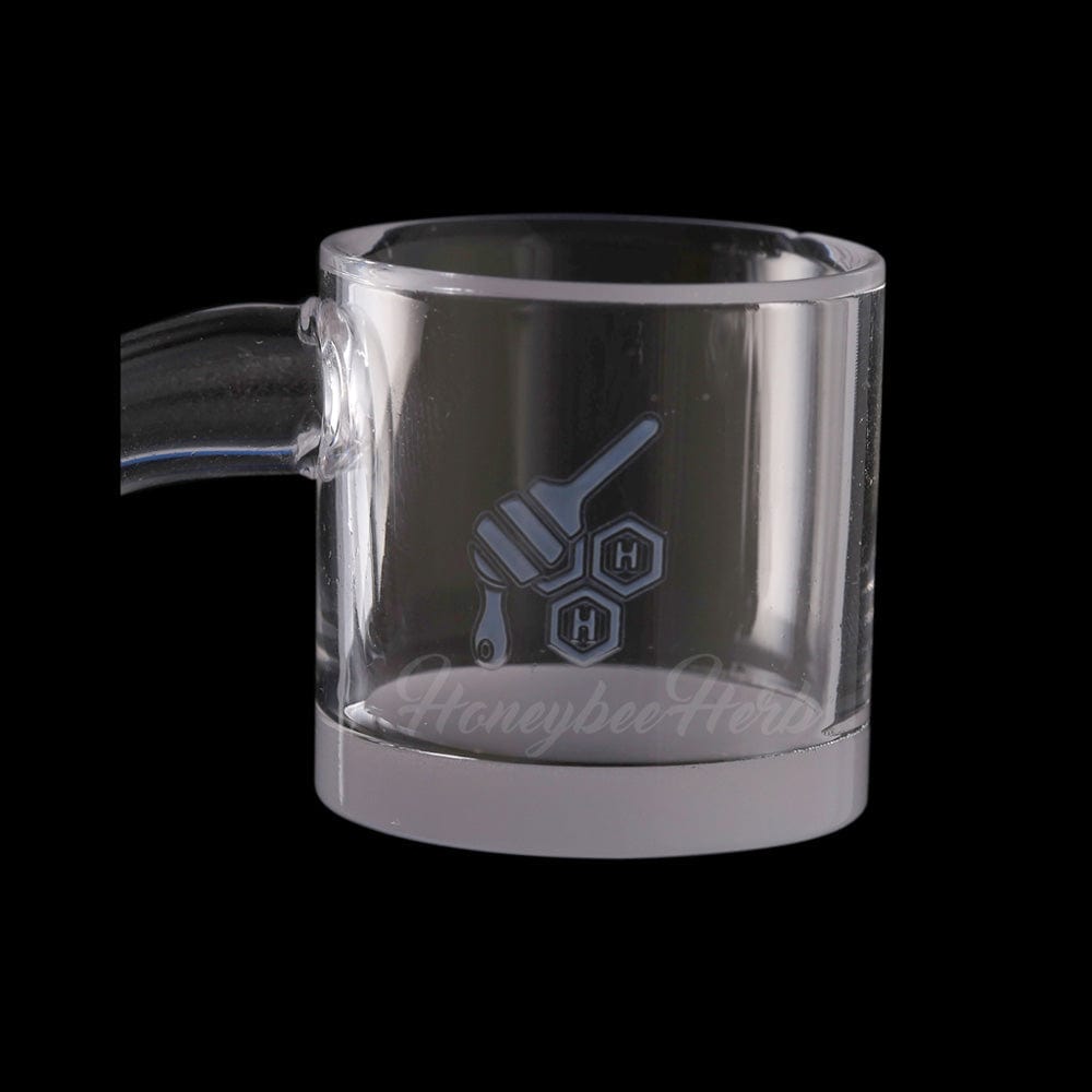 Close-up front view of the HONEY & MILK XL BEVEL QUARTZ BANGER - 90Â° DEGREE | YL showing its clear cylindrical cup, etched honey-dipper logo, and short angled neck against a black background