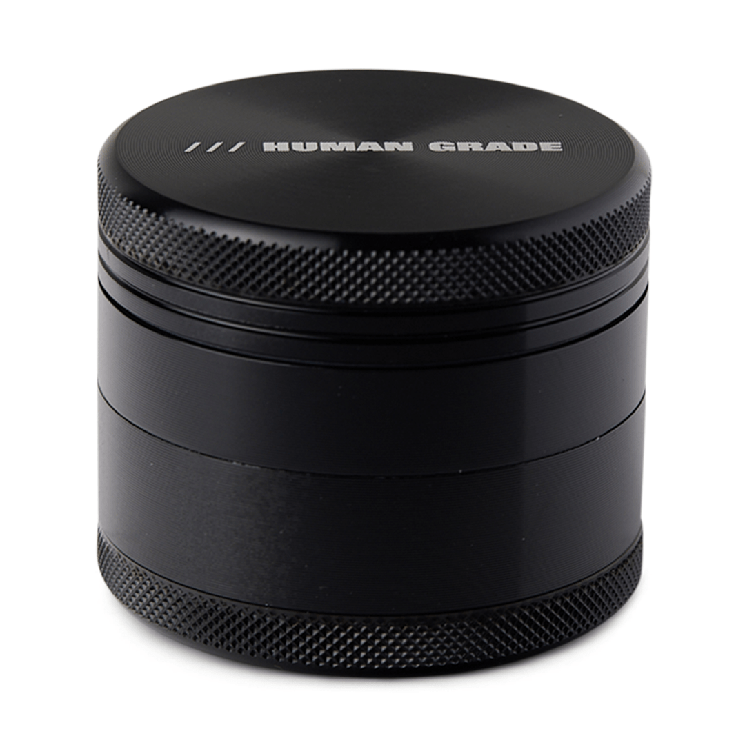 Front view of the Human Grade Grinder 1A (2"), a dark-colored, four-piece grinder with a textured cylindrical design.