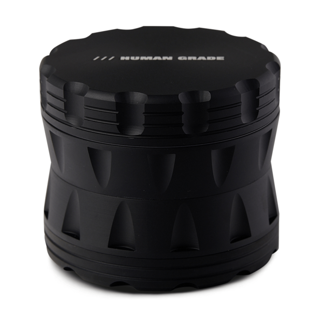 Front view of the Human Grade Grinder 2A (2.5" 4-Piece) with a dark metallic finish and a multi-tiered, geometric design.