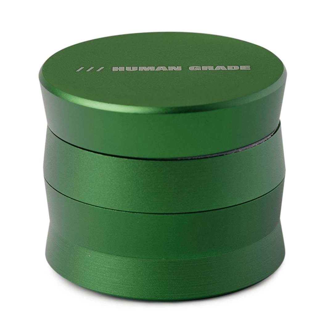A close-up studio shot of the Human Grade Grinder 3A (2" 4-Piece) in green, presenting a simple, cylindrical shape.