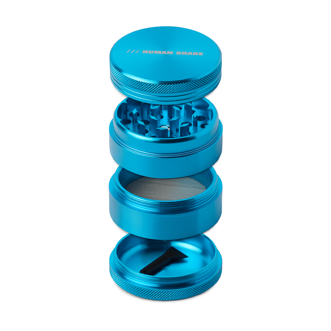 A studio shot of the disassembled Human Grade Grinder 1A (2" 4-Piece), showing each of its four metallic sections stacked vertically.