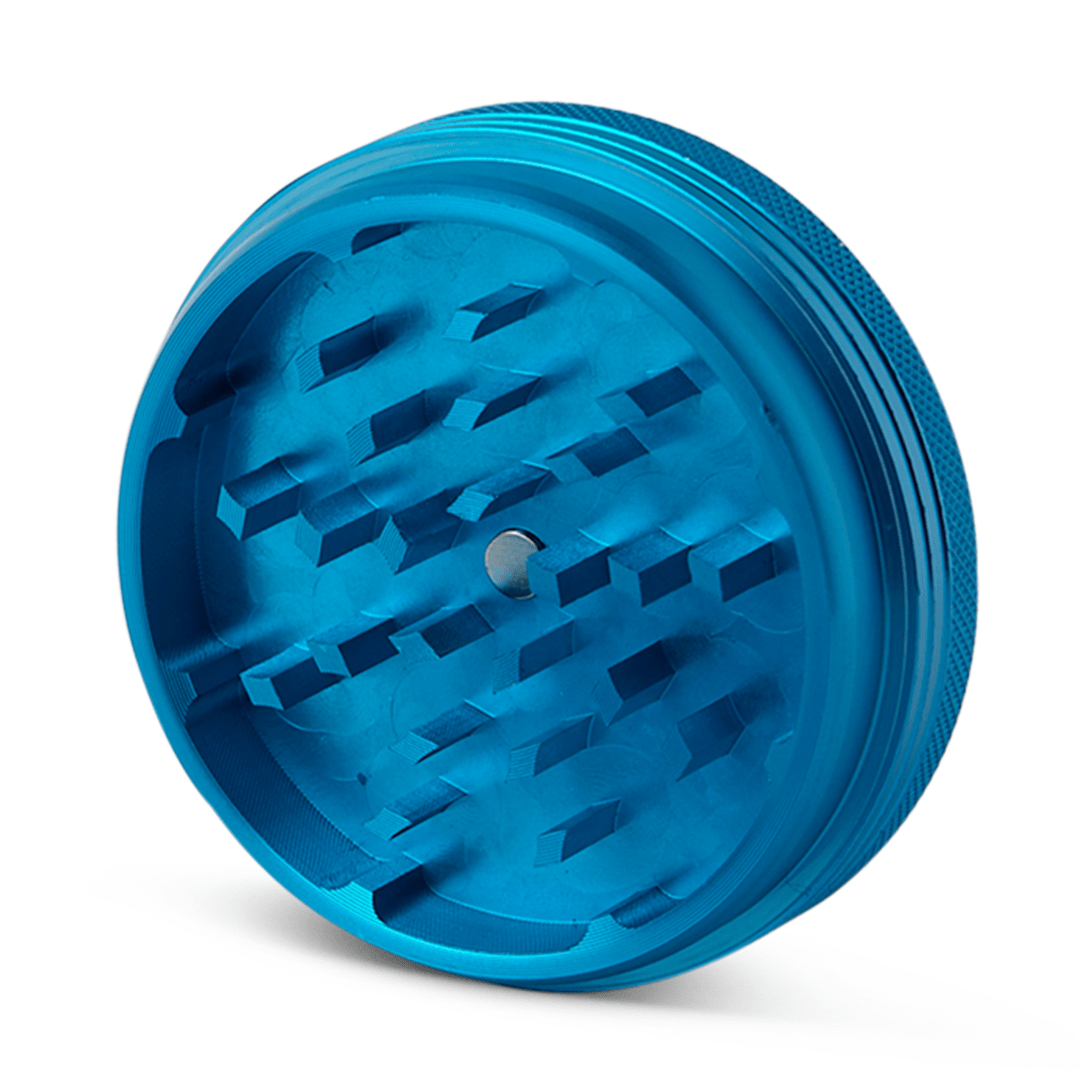 A detailed top-down view of the Human Grade Grinder 1C (2.5" 2-Piece) featuring a blue, multi-toothed grinding plate.