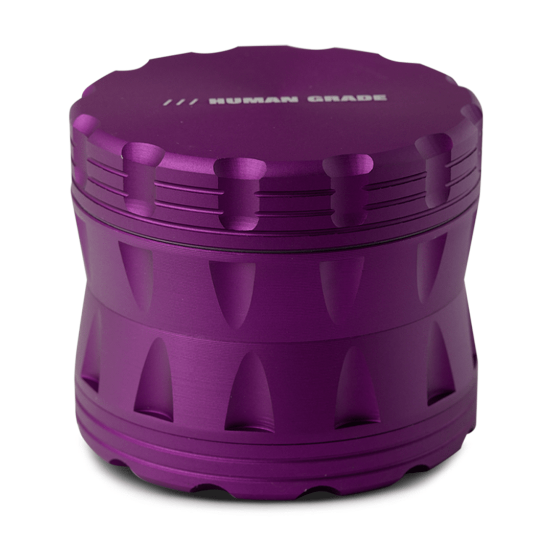 Front view of the Human Grade Grinder 2A (2.5" 4-Piece) with a ribbed purple metallic finish, angled against a dark background.
