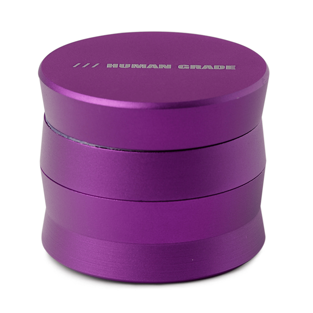 A close-up, angled view of the Human Grade Grinder 3A (2" 4-Piece) with a sleek, metallic purple finish.