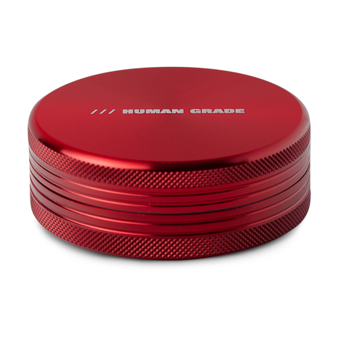 A close-up, angled view of the Human Grade Grinder 1C (2.5" 2-Piece) featuring a textured, metallic silver finish.