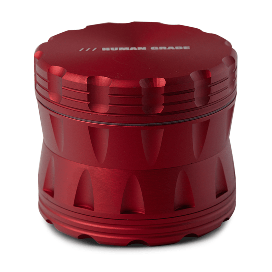 A close-up, angled view of the Human Grade Grinder 2A (2.5" 4-Piece) in red, showcasing its textured, cylindrical design.