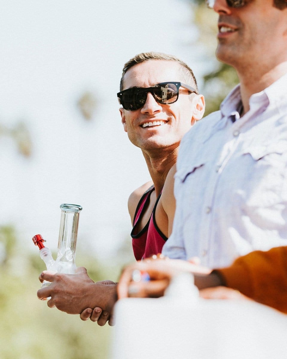 A man holds the Indestructible Bong Bowl in his hand while another man looks on, backlit by daylight.