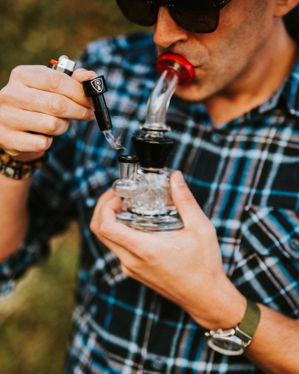 A close-up shows the Indestructible Bong Bowl being used, with smoke rising against a blurred, patterned background.
