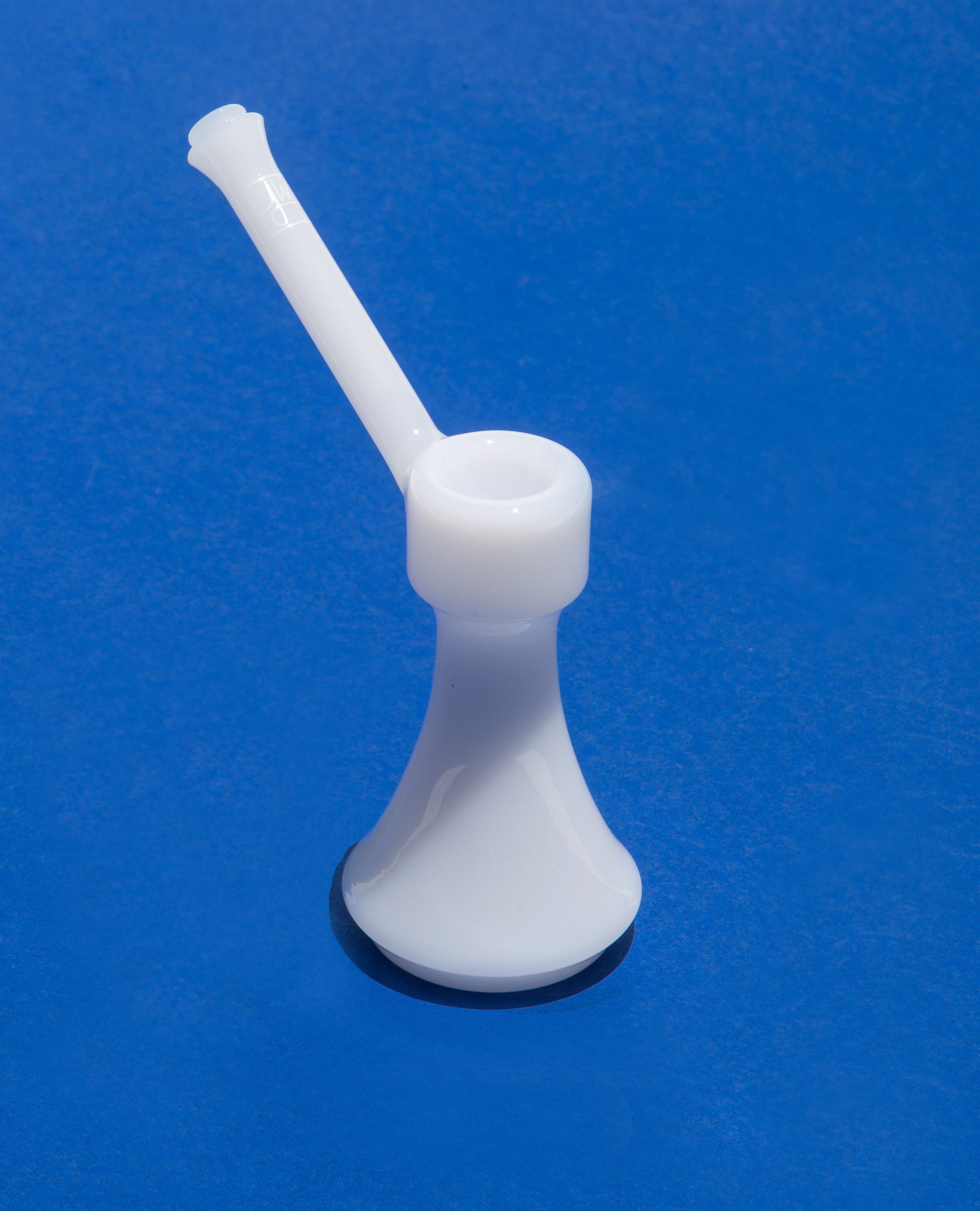 Front view of The Bubbler By Jane West, a clear glass bubbler with a simple, rounded form against a solid blue background.