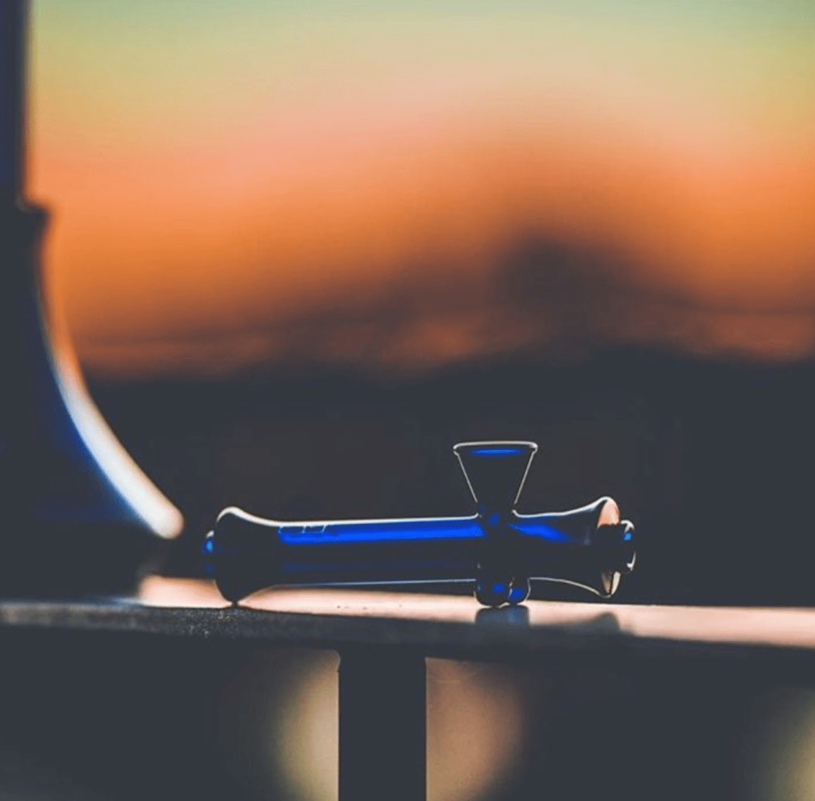 A side view of The Steamroller By Jane West, with a smooth, cylindrical shape against a blurred orange and brown background.