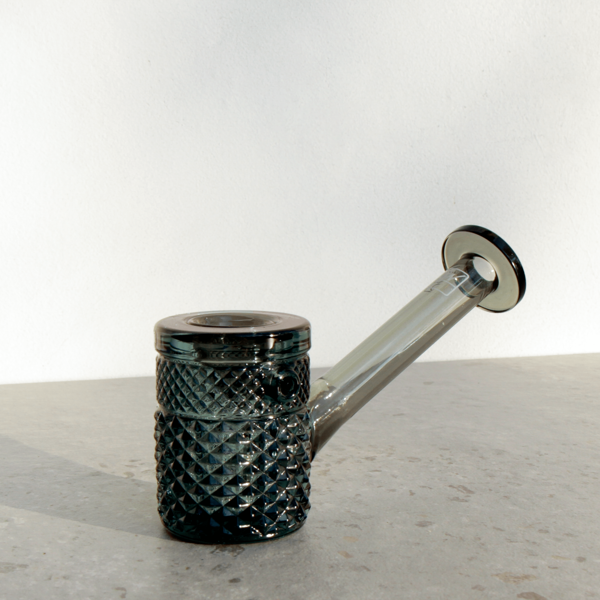 A slightly angled studio shot of the Jane West Twenties Collection Hand Pipe, featuring a textured, dark glass design.