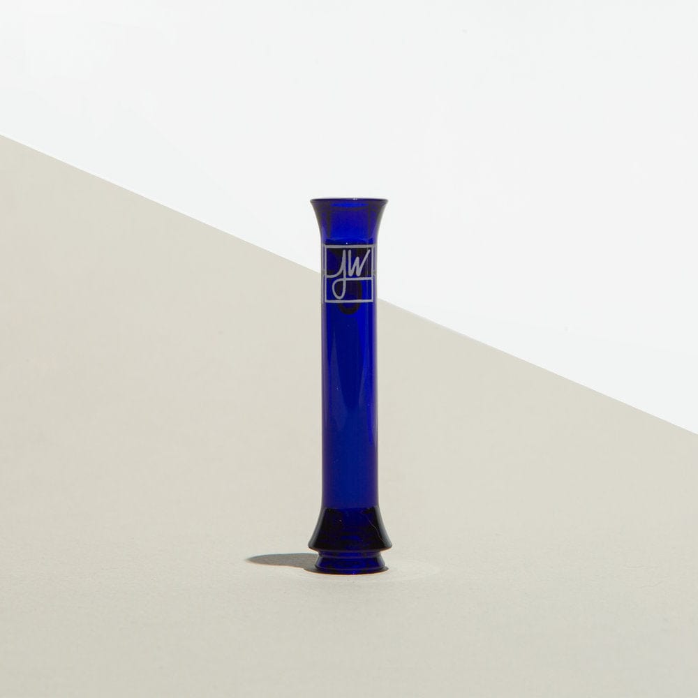 Front view of The Taster By Jane West, a blue glass piece with a narrow neck and rounded base against a light background.