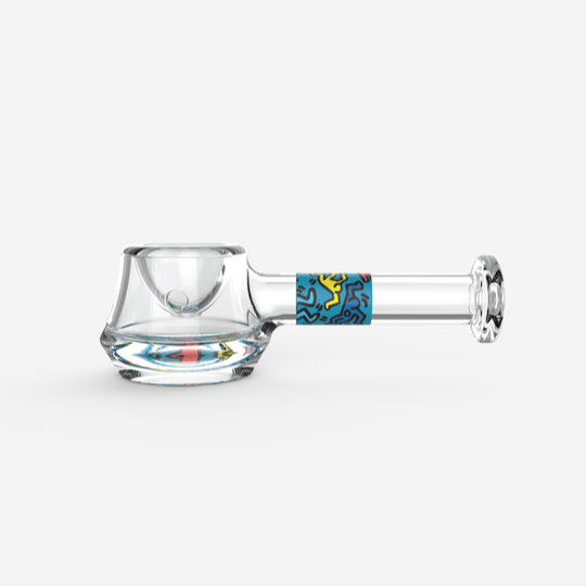 A side view of the K.Haring Spoon Pipe, showcasing its clear glass construction and curved design.