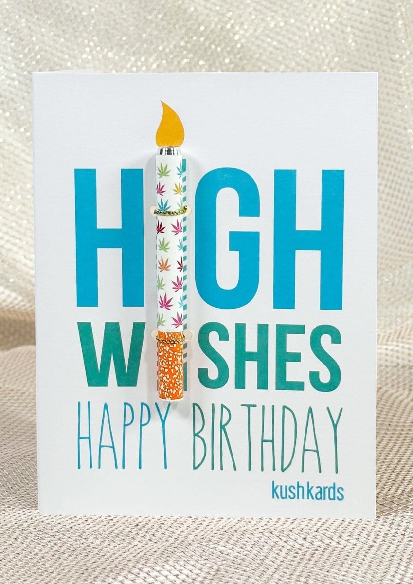 Front-facing shot of the 🎉 High Wishes Birthday Cannabis Greeting Card showing bold teal "HIGH WISHES" text with a colorful one-hitter pen clipped like a candle over "I" and a glittery fabric backdrop.