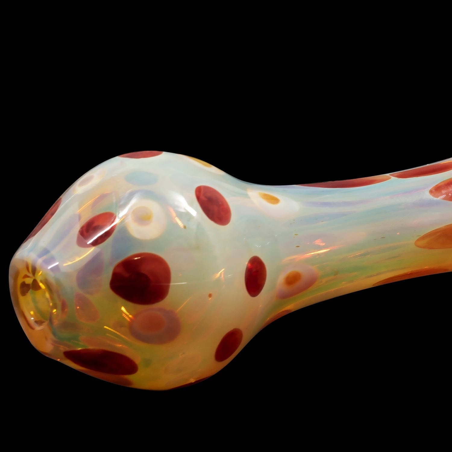 A side view of the “Polka Dot” Glass Spoon Pipe, showcasing its colorful, spotted design against a dark background.