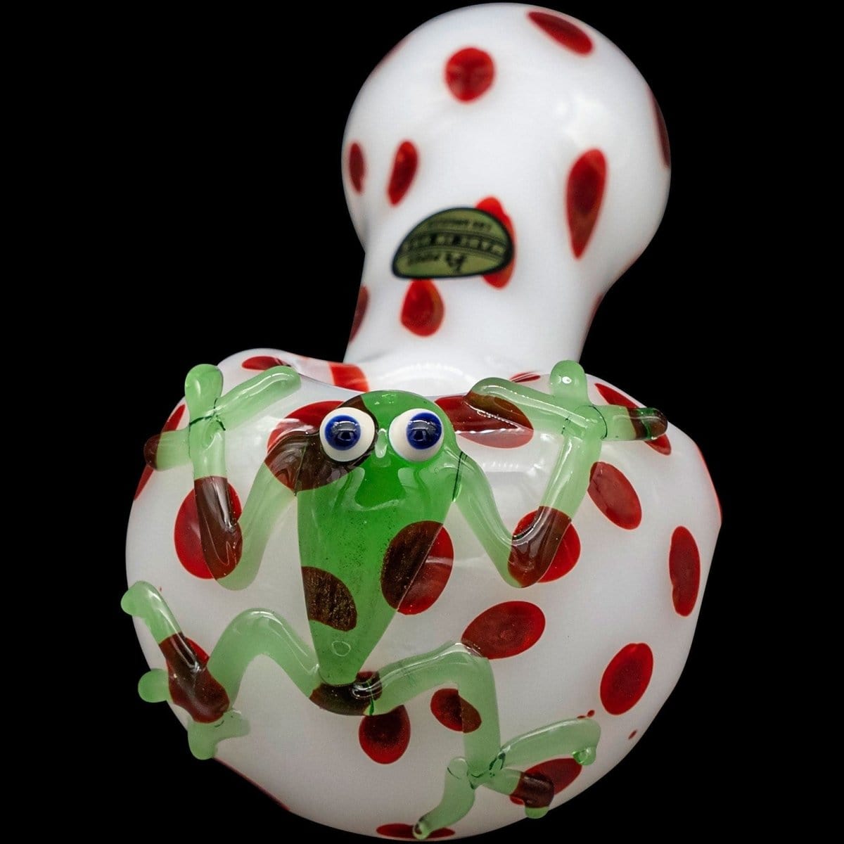 A close-up, angled view of the “Spotted Poison Frog” Spoon Glass Pipe, featuring a colorful, patterned design against a black background.