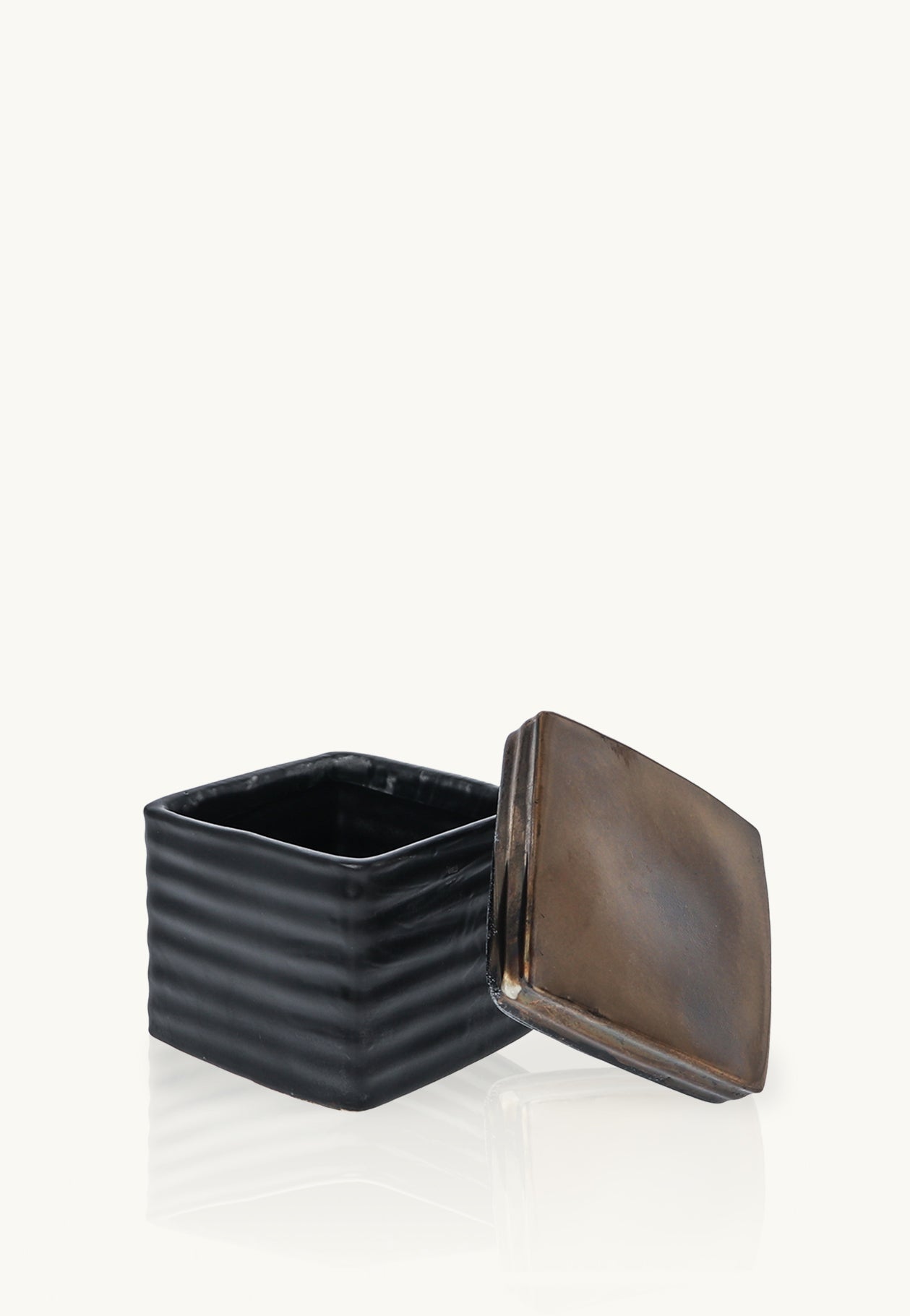 Close-up front view of the DeAngelo black ribbed square container with its bronze-toned lid propped beside it.
