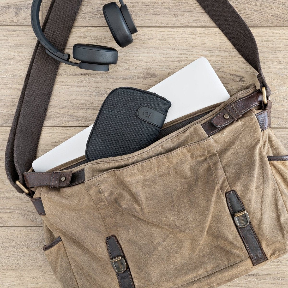 A side view shows the Carbon-lined Wallets with Combination Lock V 2.0 peeking out of a tan canvas bag alongside headphones.