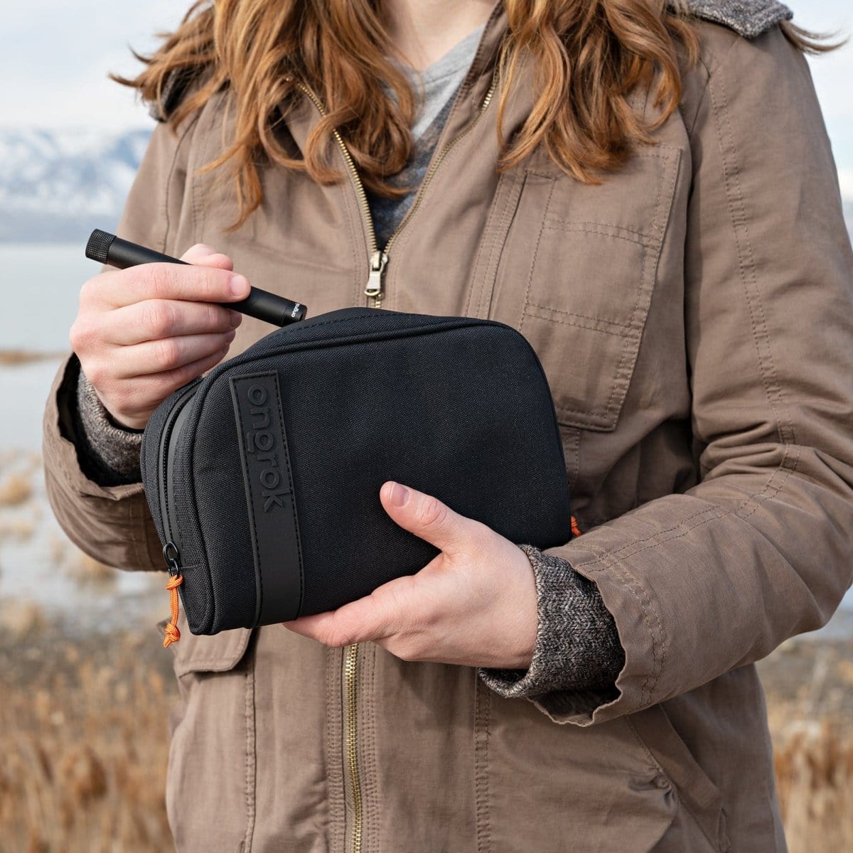 A person holds the Carbon-lined Wallets with Combination Lock V 2.0 in a slightly angled, close-up shot against a muted outdoor background.