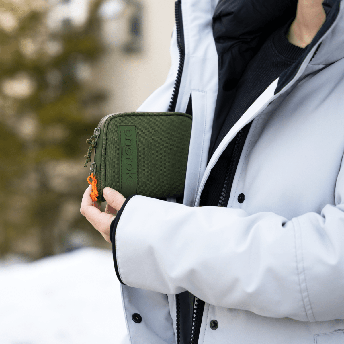 A close-up, angled view shows the Carbon-lined Wallets with Combination Lock V 2.0 held in a gloved hand against a dark jacket.
